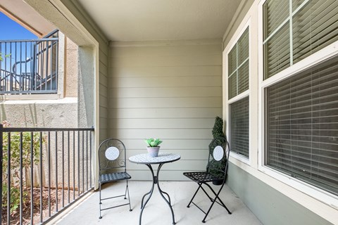 a patio with two chairs and a table on a balcony a patio with two chairs and a table on a balcony at The Millennium Towne Center Apartments, Baton Rouge, 70806